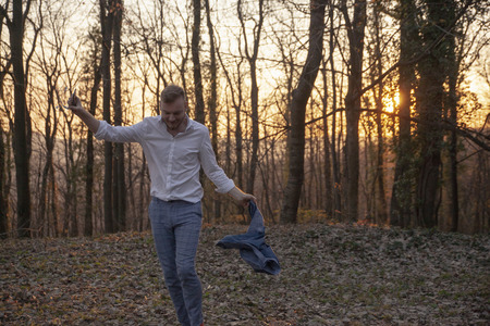 one young man carefree dancing while listening to music. alone in forest.の写真素材