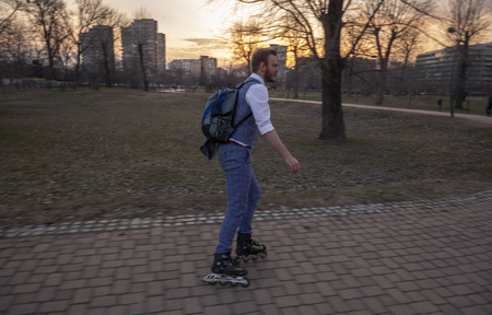 one young businessman, 20-29 years old, ridding inline skates in a park.の写真素材
