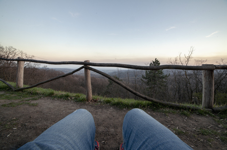 Close of shot of legs (jeans), sitting. In front is mountain range. person NOT visible, first person view.の写真素材