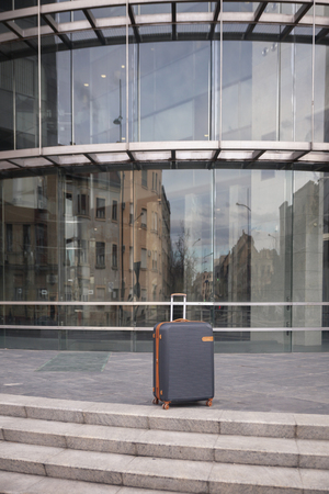 product shot, suitcase standing near a steps. modern building exterior glass wall behind.の写真素材
