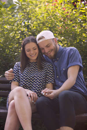 Happy couple sitting in park and holding handsの写真素材