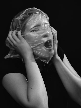 conceptual portrait, one young beautiful woman wraped in plastic sheet. Shot in studio, white background.の写真素材