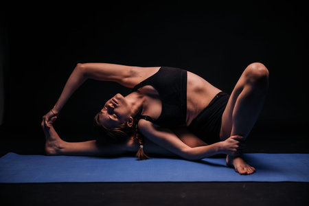 one young woman, exercising yoga, laying on a mat; calmly resting and streching in fetus position....