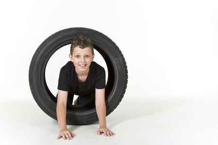Young boy is climbing through a tireの写真素材