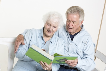 Senior couple looks at picture albumの写真素材