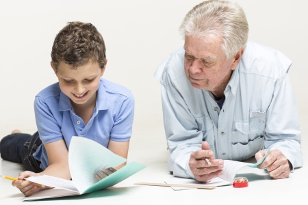 Grandfather helps his grandson with homeworkの写真素材