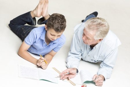 Grandfather helps his grandson with homeworkの写真素材