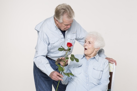 Senior man presents woman with a flowerの写真素材