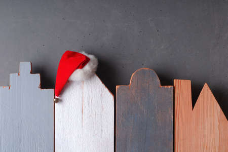 Christmas and New Year background as a symbol of the coming holiday. Silhouettes of houses carved from wood, Santa hat, copy spaceの写真素材