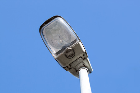 Dirty street lamp in front of a bright blue skyの写真素材