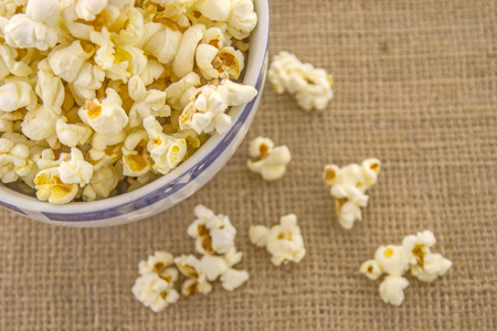 Fresh, delicious hand-popping popcorn in a bowl on a rustic jute baseの写真素材