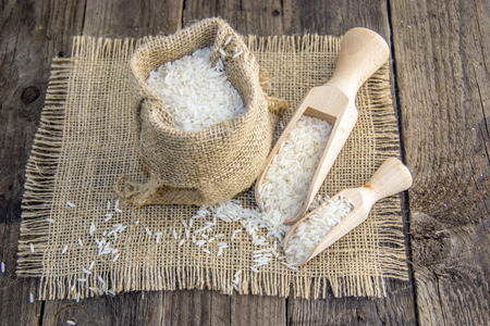 White rice in a rustic bag on a wooden surfaceの写真素材