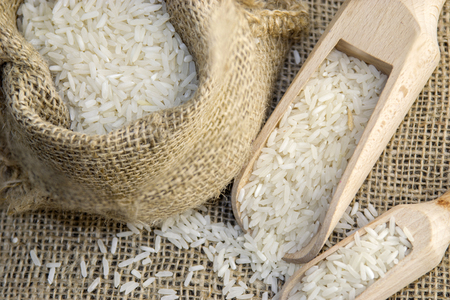 White rice in a rustic bag on a wooden surfaceの写真素材