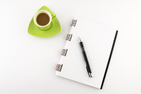 Coffee in a green cup with notes and pencil on a white background. Top view.の写真素材