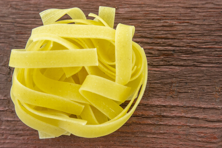 Wide cooking noodles on a wooden baseの写真素材