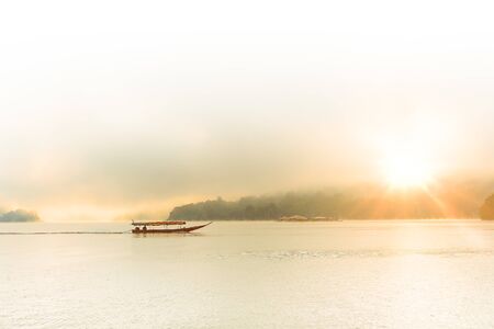 sun rising in beautiful morning with boat on the hiding lake in Chiang Mai, Thailandの写真素材