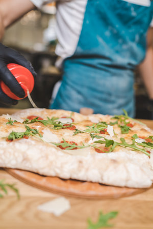 Chef making pizza in restaurant. Fresh made pizza with cherry tomatoes and arugulaの写真素材