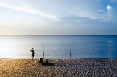 Man fishing on beach with two fishing rods at morning.の写真素材