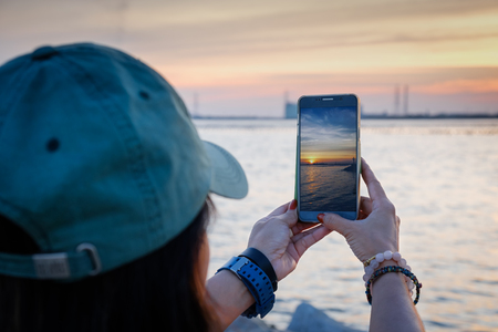 woman  taking photo beautiful time of sunset by smartphoneの写真素材