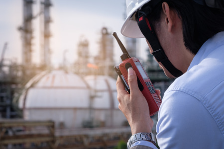 Industrial engineer working in field the petrochem plant with talking on the walkie-talkie for controlling workの写真素材
