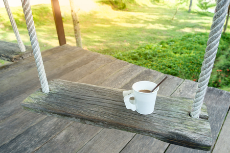 morning coffee cup on wood swing in green garden space ,relax timeの写真素材