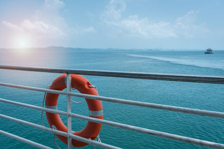 Close-up orange lifebuoy ring hanging on ferry boat with ocean backgroundの写真素材