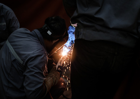 worker with protective mask welding metal and sparks,worker weld metal in factoryの写真素材