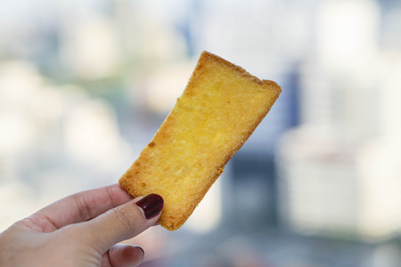 a piece of baked crispy butter bread in human handの写真素材