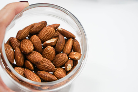 close up a transparent bowl of almonds in handの写真素材