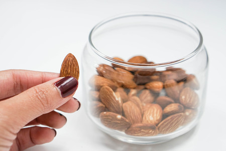 holding an almond from the transparent bowlの写真素材