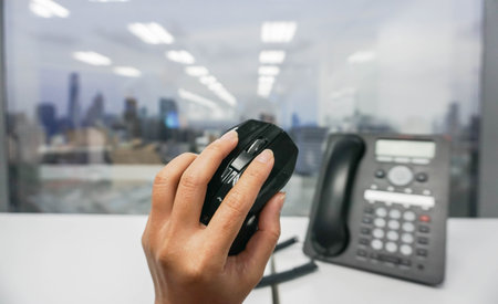 Hold computer mouse in hand with IP phone background