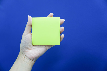 Hold mockup postit in hand with blue backgroundの写真素材