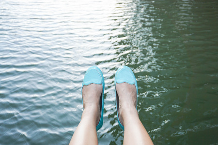 Woman with green shoes sit aside the riverの写真素材