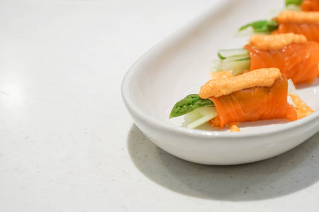 Close up the salmon roll with cucumber asparagus and spicy sauce on top