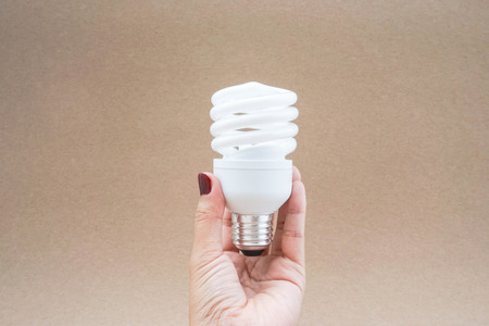Twist and spiral LED light bulb in hand with brown backgroundの写真素材