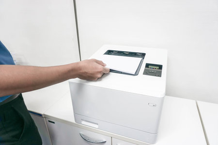 businessman in blue shirt put paper sheet into printer for business document copy