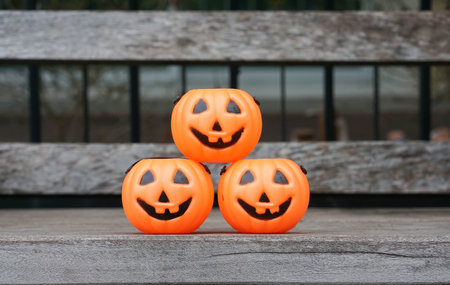 three orange Jack-O-Lantern stack on wooden benchの写真素材