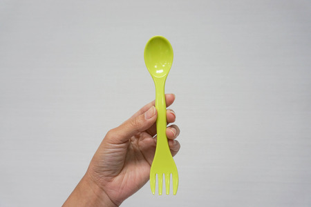 two in one green spoon and fork in woman left handの写真素材