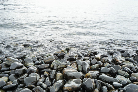 round stones at the seashore with sea wavesの写真素材