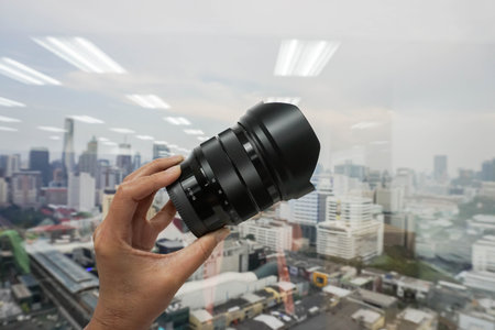 woman hold camera lens in hand with city view backdrop