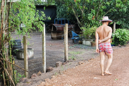 farmer wearing loincloth with hat walk barefoot on dirt road to his houseの写真素材