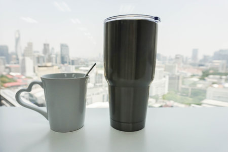 white ceramic mug and water stainless glass on office deskの写真素材