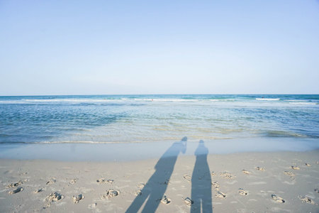 shadow of couple on the sand at seaside with blue sky