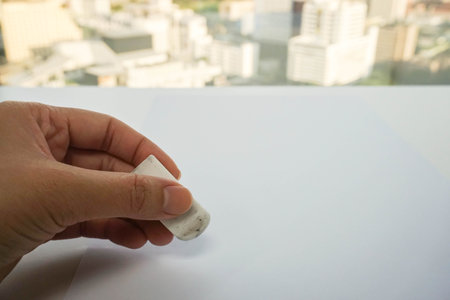 close up people hand use eraser on mock up paper sheet for mistake removal