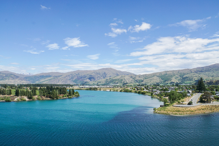 clear blue Tekapo lake with tall pine and mountain rangeの写真素材