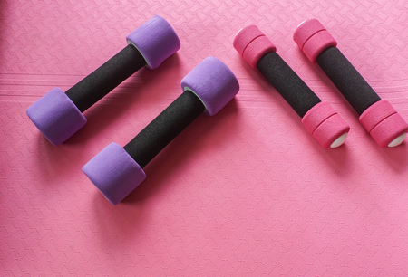 small pink and big violet dumbbell on yoga mat for women exerciseの写真素材