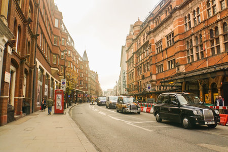 London / UK - 22 November 2017: vintage building along road with black cab in sunsetのeditorial素材