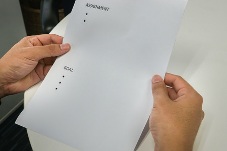 business concept - close up employee hold mock up paper of assignment and goals for performance reviewの写真素材