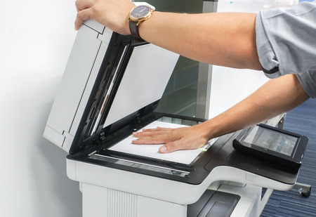 close up businessman use printer glass plate to scan important and confidential documents in officeの写真素材