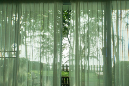 white transparent curtain at the house door with sea view and green yardの写真素材